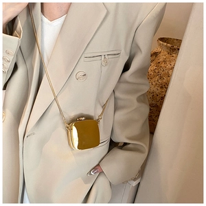 Close-up of a mini gold metallic crossbody bag with sleek snake chain on a model