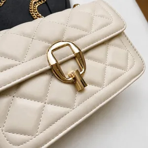 Close-up of quilted cream leather shoulder bag with glossy gold metal clasp and chain