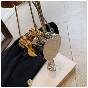 Close-up of heart-shaped metallic clutch bags with ornate bee clasp and snake chain straps