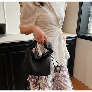 Minimalist black quilted cloud handle underarm handbag worn with a casual outfit