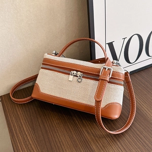 Retro canvas and brown leather box handbag with adjustable strap on a wooden table
