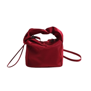Modern red nylon handbag with knotted handle and shoulder strap shown in a front view