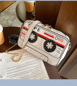 Détail d'un sac bandoulière rétro en forme de cassette avec fermetures éclair dorées