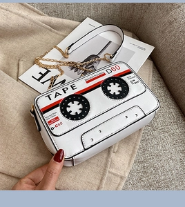 Gros plan d'un sac cassette blanc avec design TAPE et bandoulière chaîne dorée