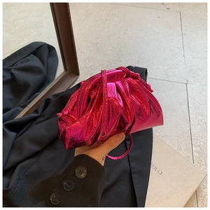 Close-up of metallic pink pleated cloud bag with a matching thin shoulder strap