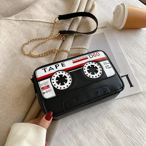 Sac bandoulière rétro en forme de cassette avec chaîne dorée sur manteau beige et revue