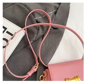 Dettaglio di borsa in pelle rosa con fibbia dorata e tracolla regolabile