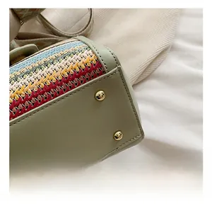 Detail of colorful woven straw bag with gold feet studs and green leather base