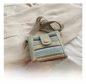 Detail of woven light green crossbody bag with rainbow patterns and ethnic strap
