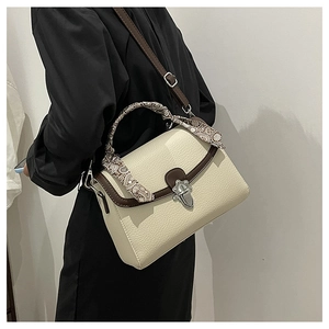 Detail of cream lychee leather handbag with decorative silk scarf and silver metal buckle