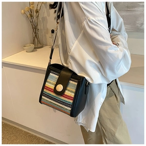 Detail of woven crossbody bag with colorful stripes and circular wooden buckle accent