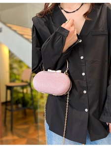 Détail de la pochette de soirée rose pailletée avec nœud doré et chaîne en métal