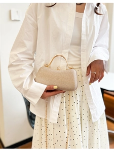 Pochette de soirée à paillettes champagne avec poignée métallique portée par un mannequin