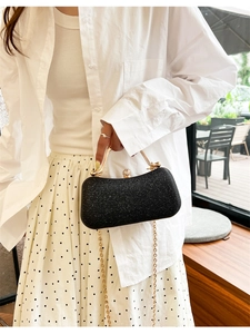 Pochette de soirée noire pailletée avec poignée dorée et bandoulière sur modèle