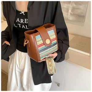 Detail of brown leather crossbody bag with colorful woven pattern and wide ethnic strap
