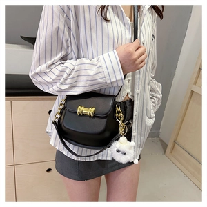 Elegante borsa a tracolla nera con fibbia dorata e ciondolo in peluche bianco su modella