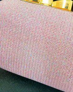 Detailed close-up of pink sequin fabric with gold metal trim on a sparkling evening bag