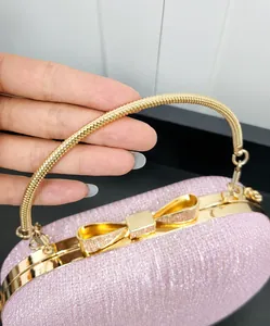Detail of pink glitter evening bag featuring gold spiral handle and bow-shaped clasp