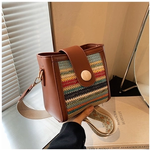 Detail of bohemian striped bucket bag with brown leather trim and wide ethnic strap