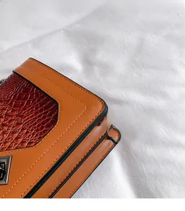 Detail of snake skin pattern stitching and metal lock on the brown shoulder bag
