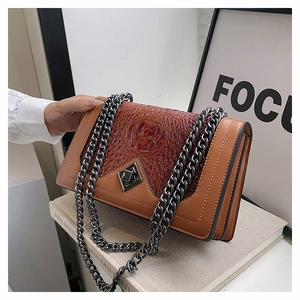 Detail of snake skin texture and metal chain strap on brown crossbody bag