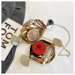 Macro view of gold metal evening clutch interior showing compact makeup storage and chain