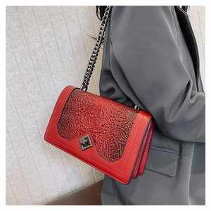 Detail of red faux-crocodile leather handbag with grey metal chain and geometric lock