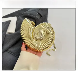 Detail view of a golden conch-shaped evening bag featuring a spiral texture and chain strap