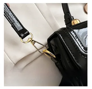 Gros plan du crochet en métal doré sur un sac à bandoulière en cuir verni noir