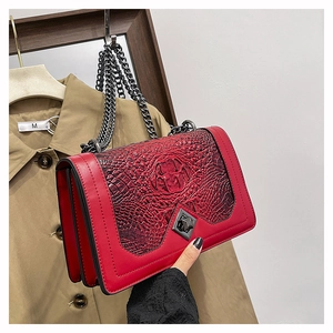 Close-up of red crocodile pattern shoulder bag with silver chain and geometric metal buckle