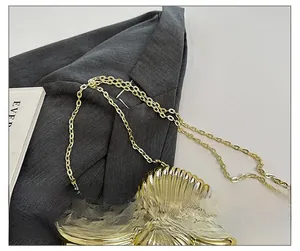 Close-up of golden shell evening bag with radial texture and fine metal chain strap
