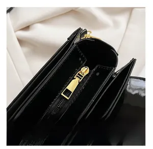 Détail de la fermeture éclair dorée lisse sur un sac à main en cuir verni noir de qualité