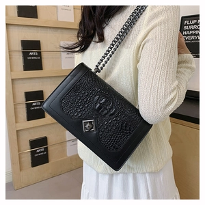 Detail of black snake pattern shoulder bag with silver geometric lock and chain strap