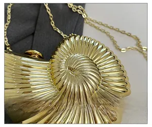 Detail of metallic gold shell evening bag featuring radial texture and fine chain strap