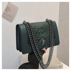 Detail of dark green crocodile texture shoulder bag with metallic chain and lock