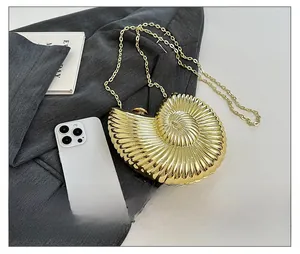 Golden nautilus shell clutch bag with metallic texture shown next to a smartphone