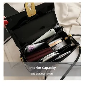 Vue macro de l'intérieur d'un sac en cuir verni noir avec serrure dorée et sections