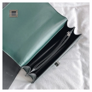 Detail of dark green matte leather bag featuring a three-layer interior and silver lock