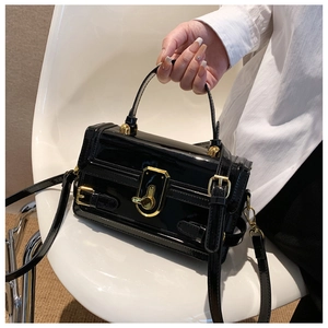 Détail du sac en cuir verni noir brillant avec garnitures dorées et accents sphériques