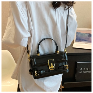 Détail du sac bandoulière en cuir verni noir avec boucle dorée et fine lanière