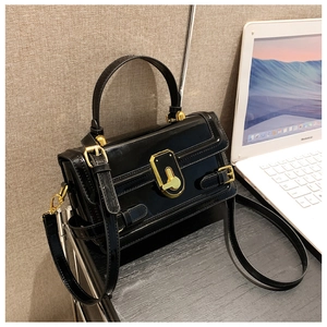 Détail du sac à main en cuir verni noir avec fermoir vintage doré et poignée chic