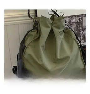 Detail of sage green drawstring bucket bag with silver buckles on a wooden table