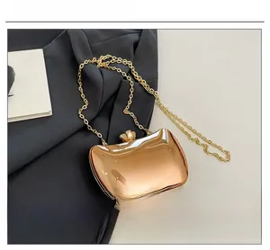 Detail of rose gold hard shell evening bag with metallic chain on a stylish suit