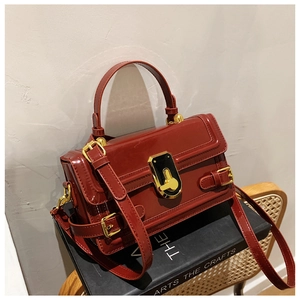 Détail d'un sac à main en cuir verni bordeaux avec fermoir doré et poignée chic