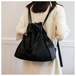 Detailed back view of model wearing a black minimalist canvas bucket bag with drawstrings