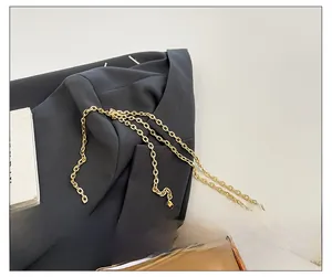 Detailed close-up of premium gold metal chain strap on minimalist textured evening bag