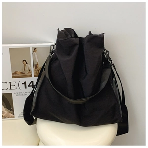 Detail of black nylon tote bag featuring adjustable wide strap and drawstring closure