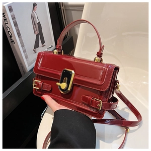 Vue détaillée du sac à main en cuir verni rouge avec finition brillante et boucle dorée