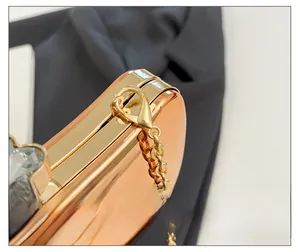 Detail of rose gold metal clutch featuring crystal inlay and high-shine mirror finish