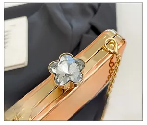 Detail of rose gold evening bag featuring a floral rhinestone clasp and metal chain